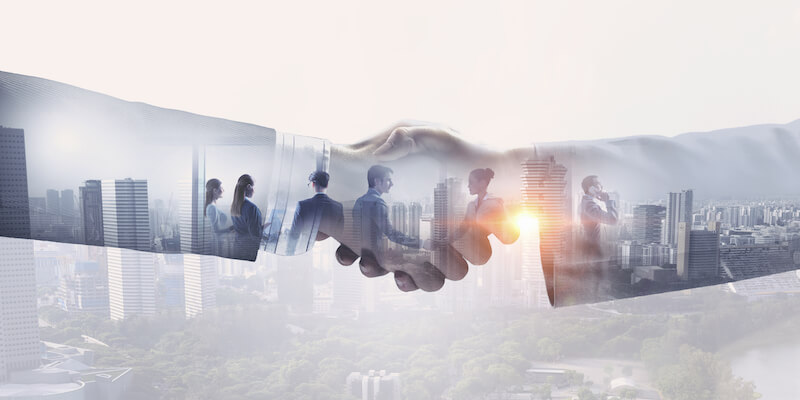 Business success image of people shaking hands overlaying a picture of a city